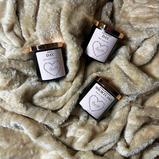 The Candle Trios Bundle includes three soy candles in 8oz matte black jars with rose gold lids on a textured beige background.