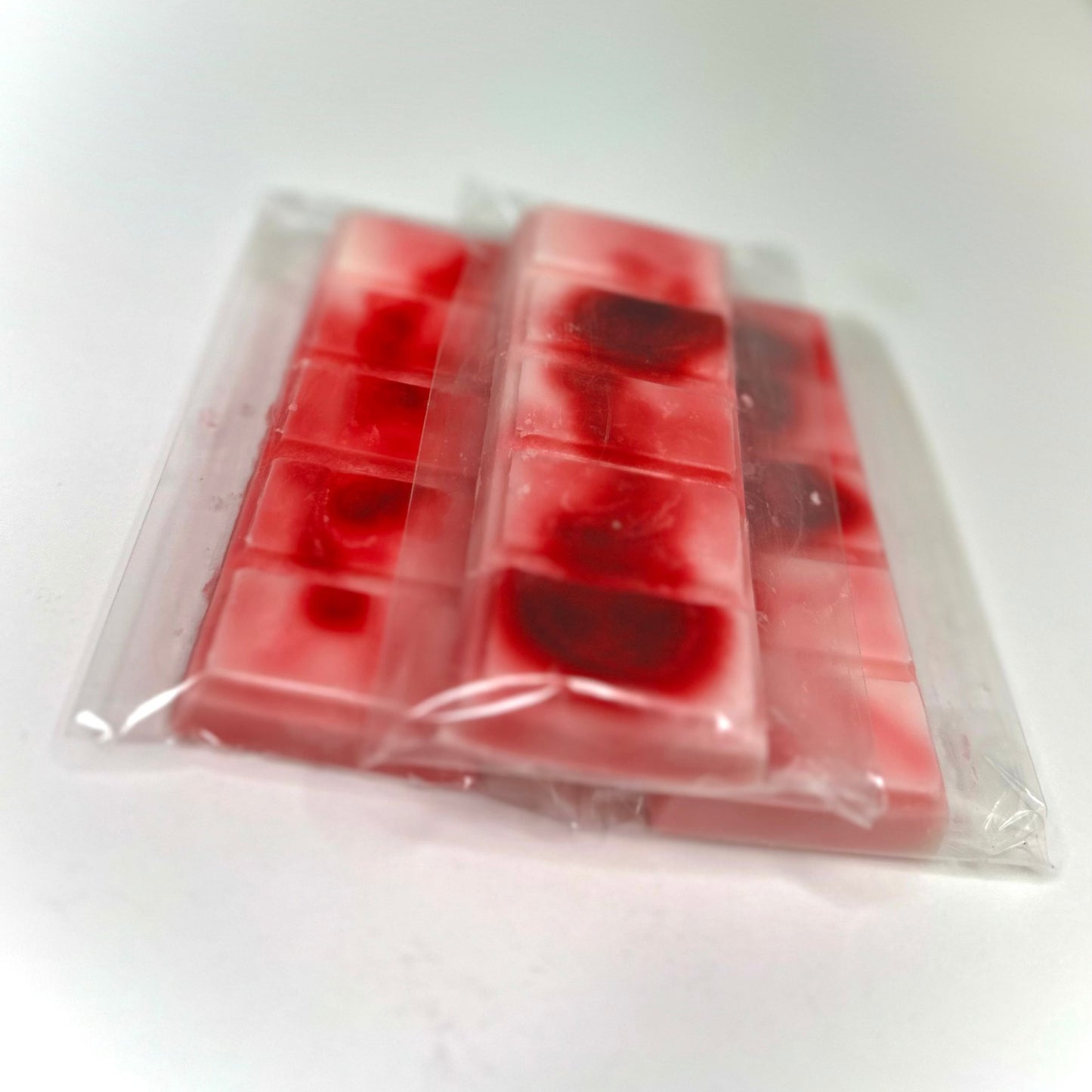Three strawberry shortcake (pink and red abstract color) wax melt bars on white background.
