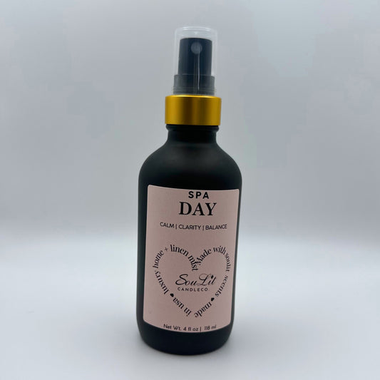 Air and linen freshener mist in 4oz matte black glass bottle with a gold neck and clear top on white background. 