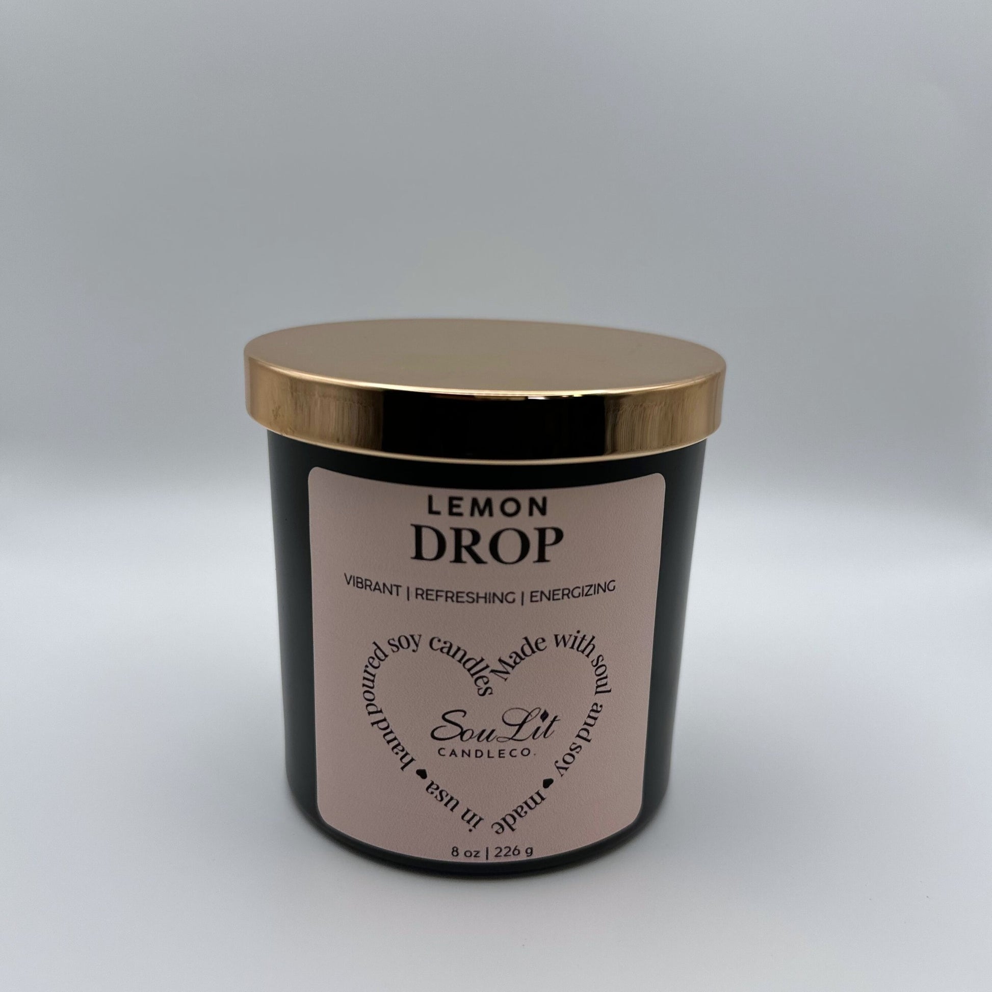 Soy candle in 8oz matte black glass jar with rose gold lid on white background. 