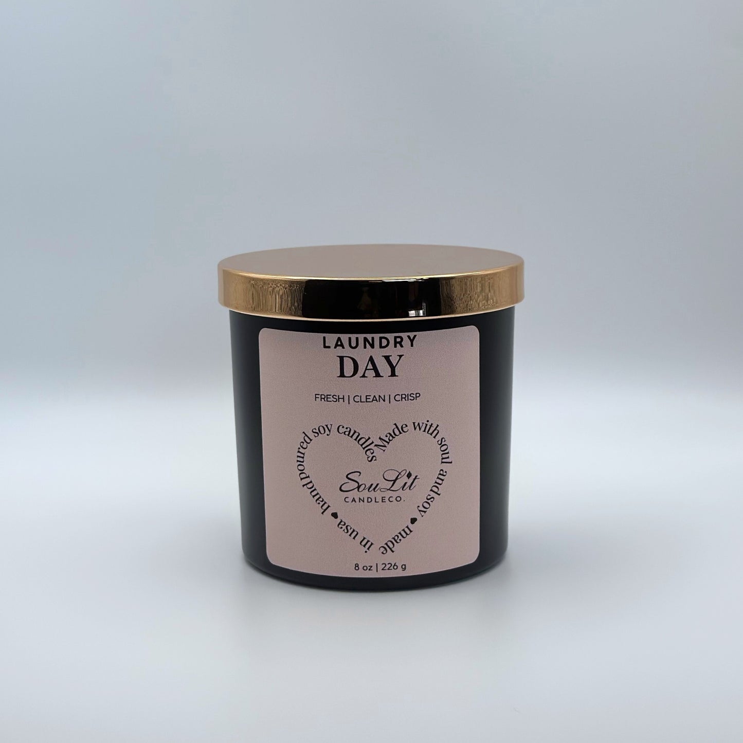 Soy candle in 8oz matte black glass jar with rose gold lid on white background. 