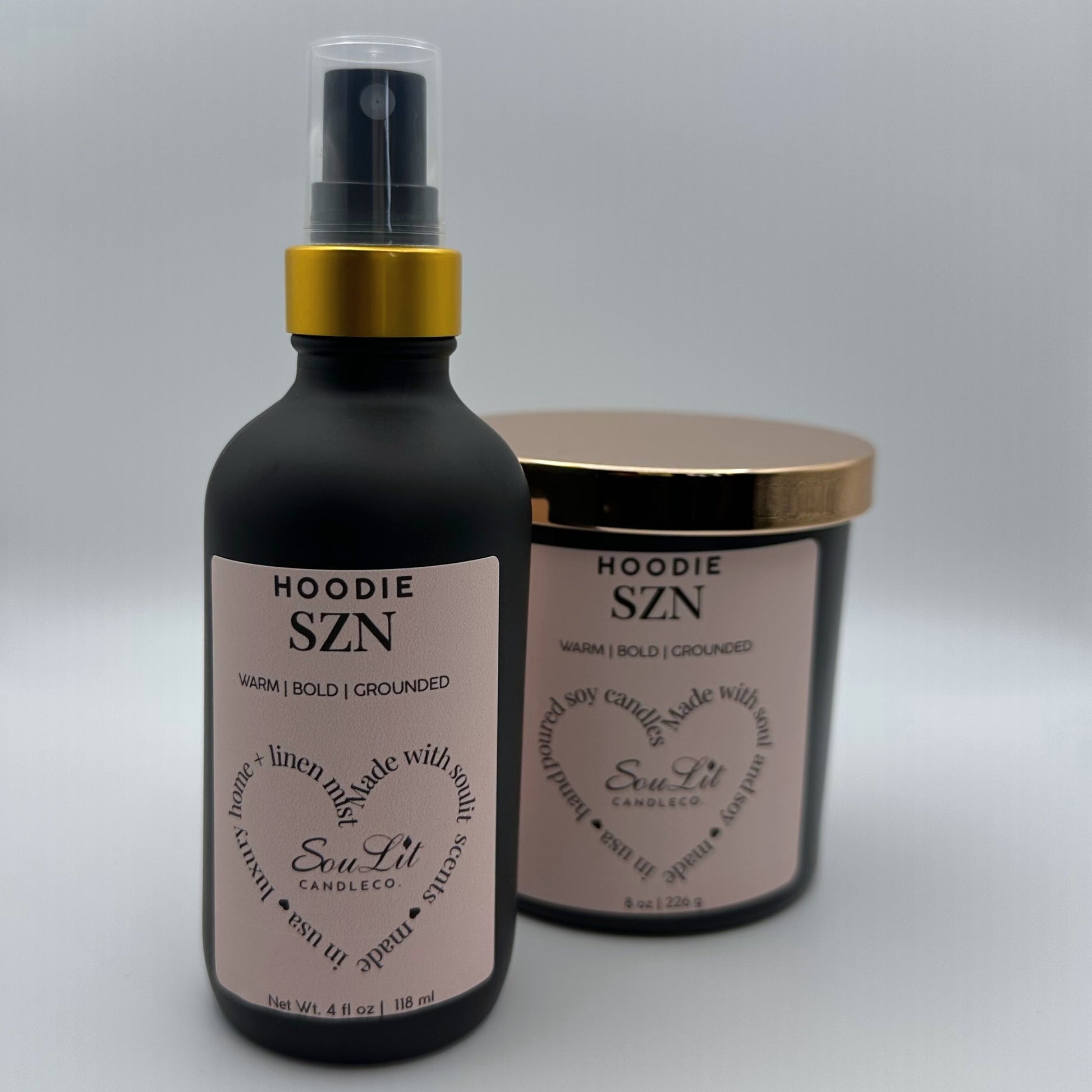Air and linen freshener mist in 4 oz matte black glass bottle with  gold neck and a Soy candle in 8oz matte black glass jar with rose gold lid on white background. 