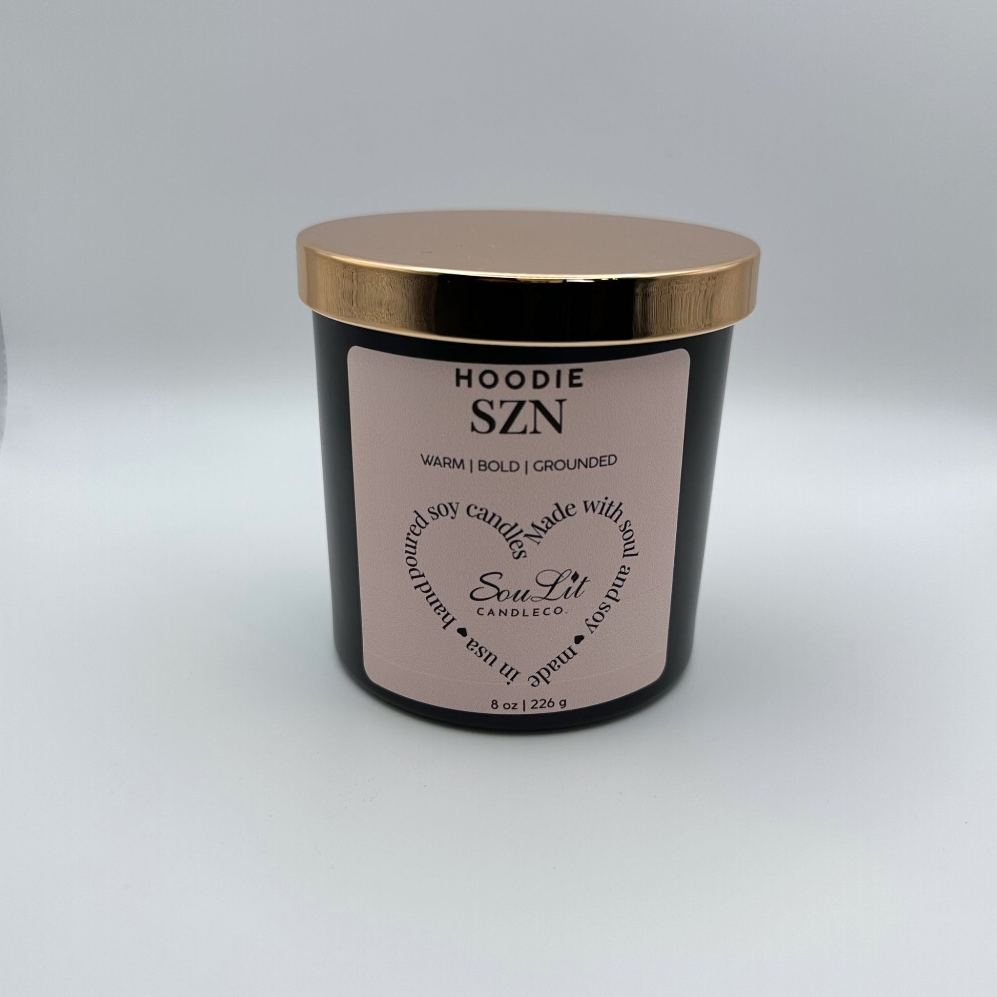 Soy candle in 8oz matte black glass jar with rose gold lid on white background. 