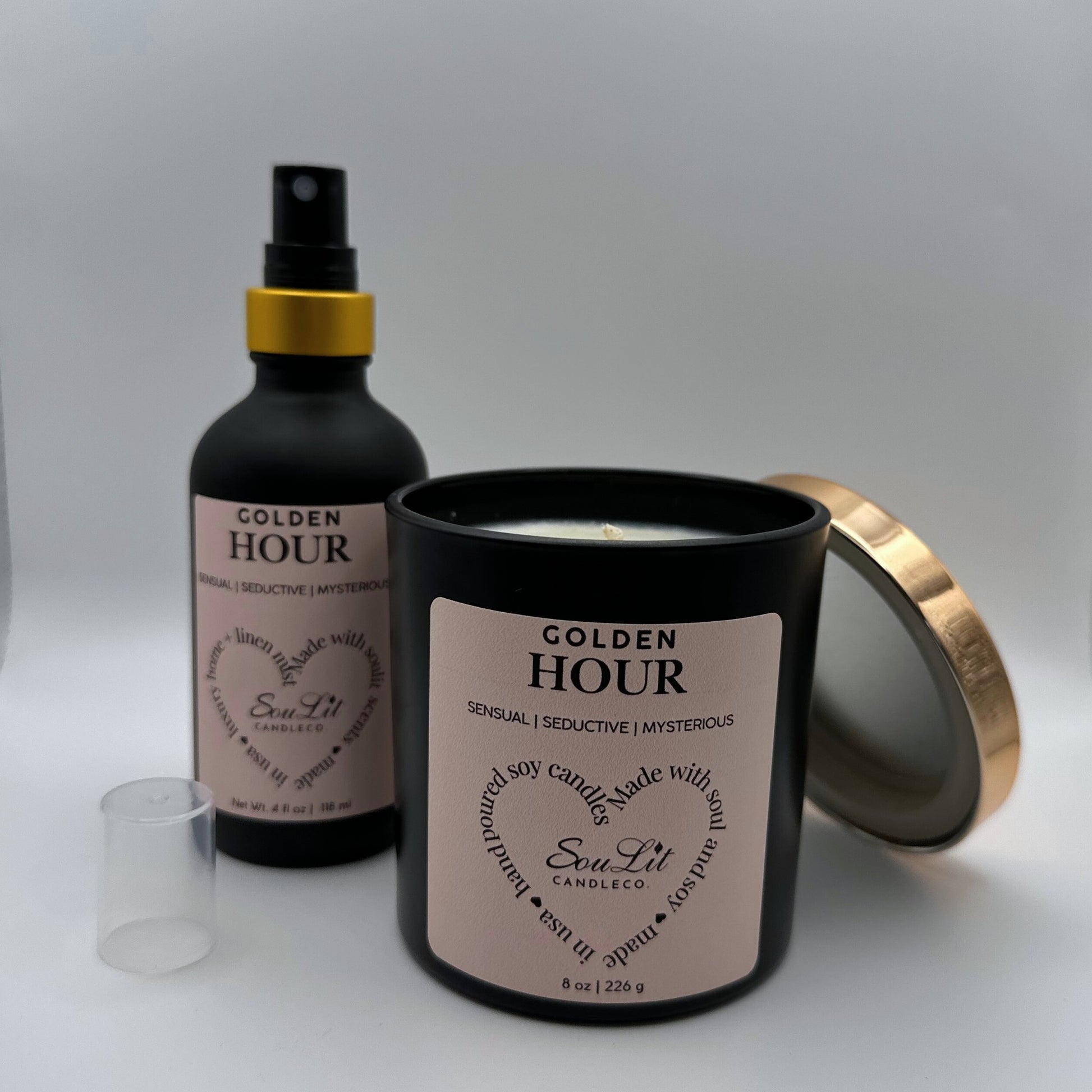Air and linen mist in 4 oz matte black glass bottle with  gold neck and a Soy candle in 8oz matte black glass jar with rose gold lid off propped on the side of jar on white background. 
