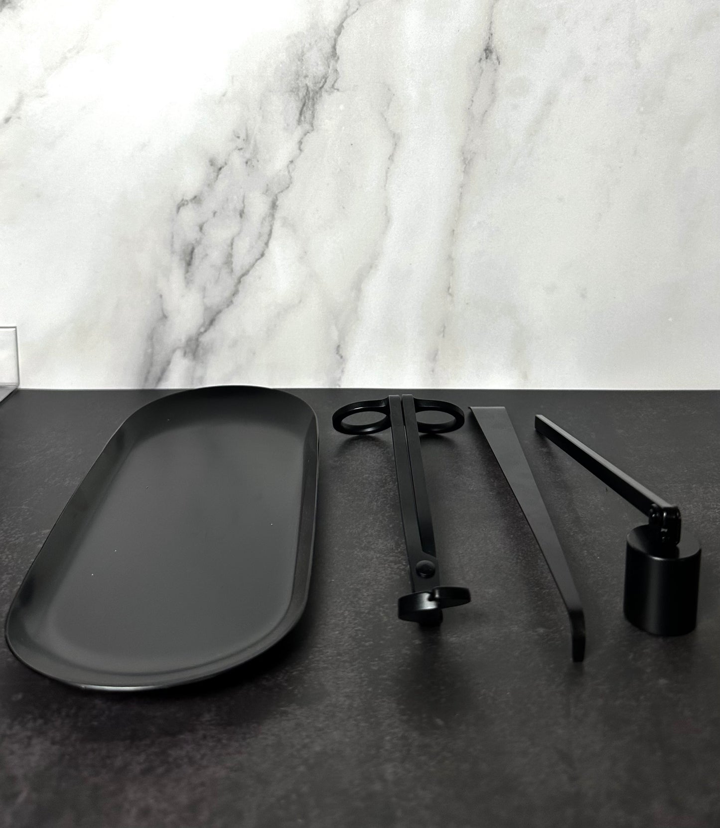 Semi-gloss black 4-piece candle care kit laid out showing a wick trimmer, snuffer, dipper, and tray. 