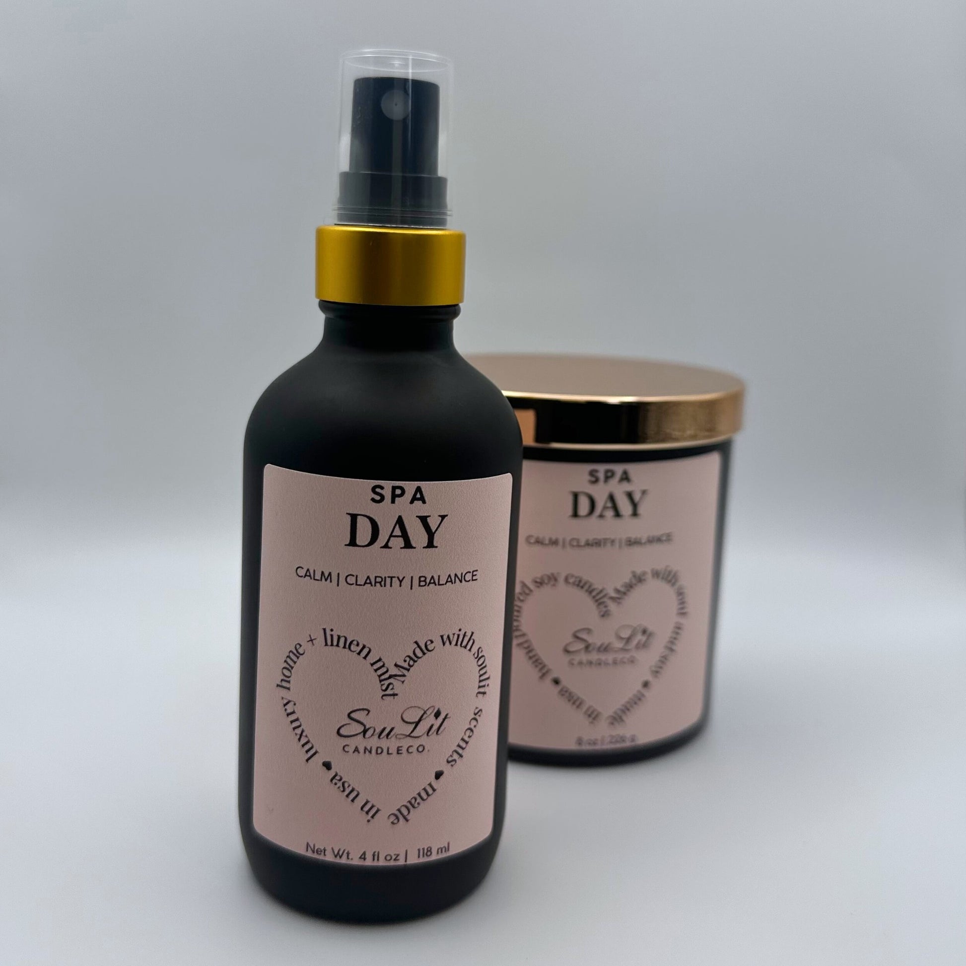 Air and linen freshener mist in 4 oz matte black glass bottle with  gold neck and a Soy candle in 8oz matte black glass jar with rose gold lid on white background. 