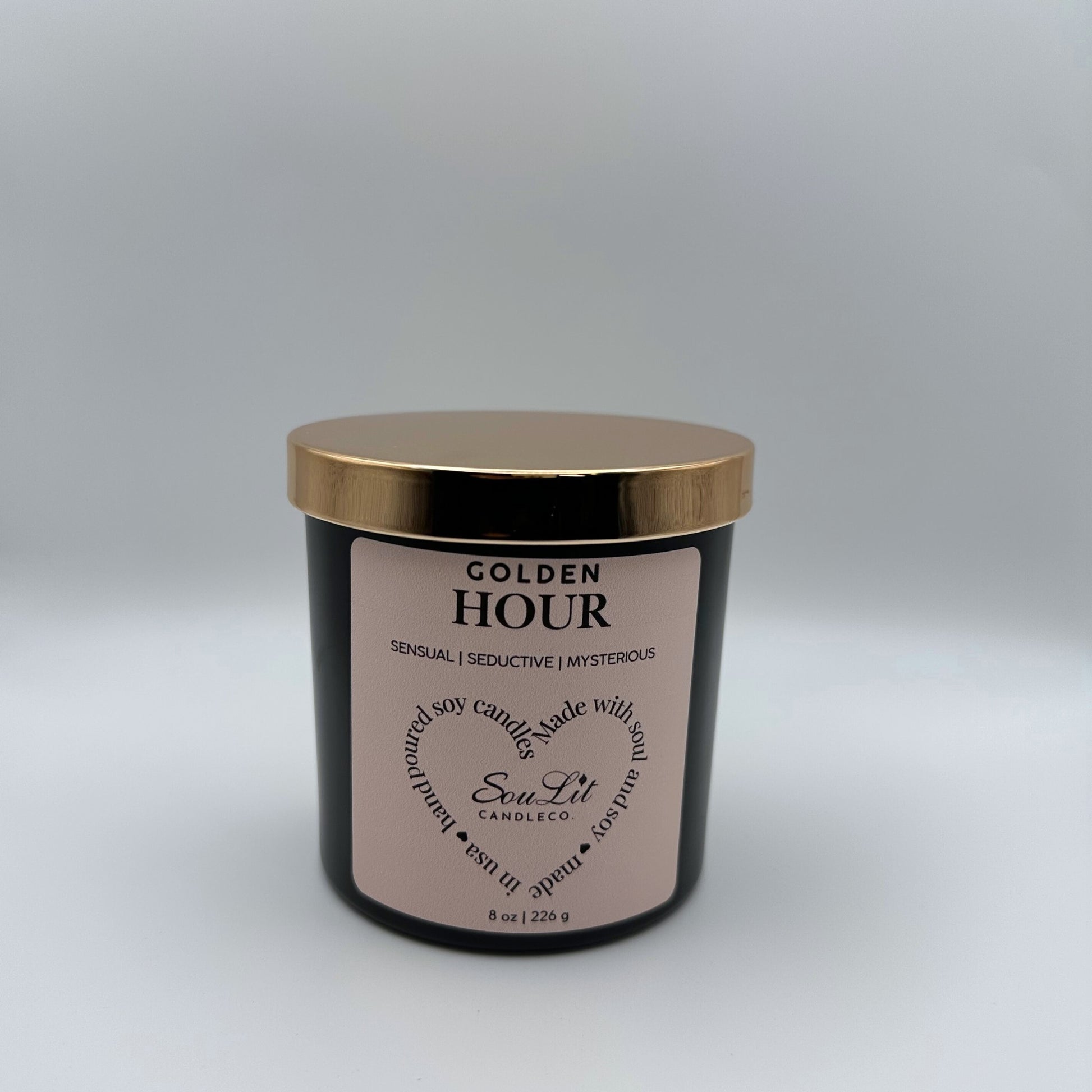 Soy candle in 8oz matte black glass jar with rose gold lid on white background. 