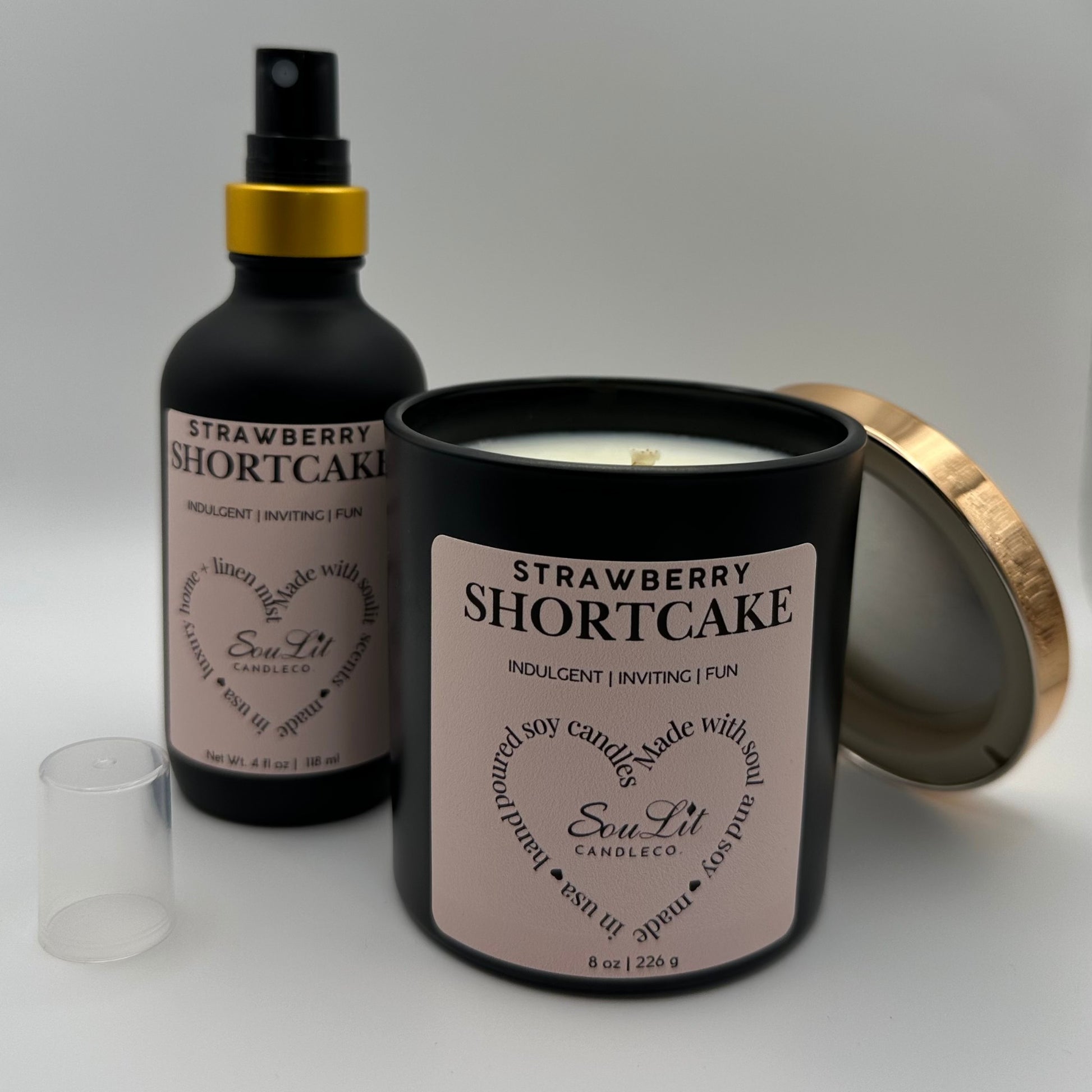 Air and linen mist in 4 oz matte black glass bottle with  gold neck and a Soy candle in 8oz matte black glass jar with rose gold lid off propped on the side of jar on white background. 