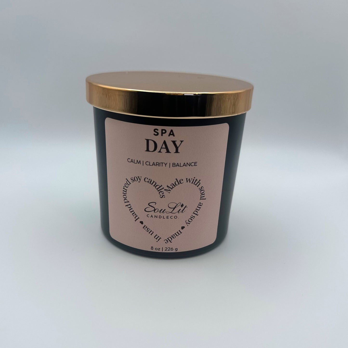 Soy candle in 8oz matte black glass jar with rose gold lid on white background. 
