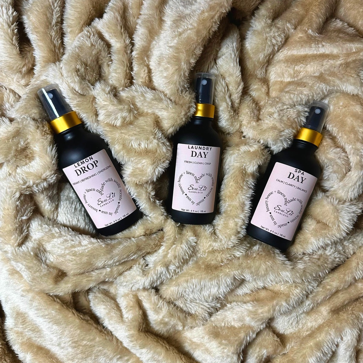 The Mist Trios Bundle includes three Air and linen mist in 4oz matte black glass bottles with a gold neck on a texture beige background. 