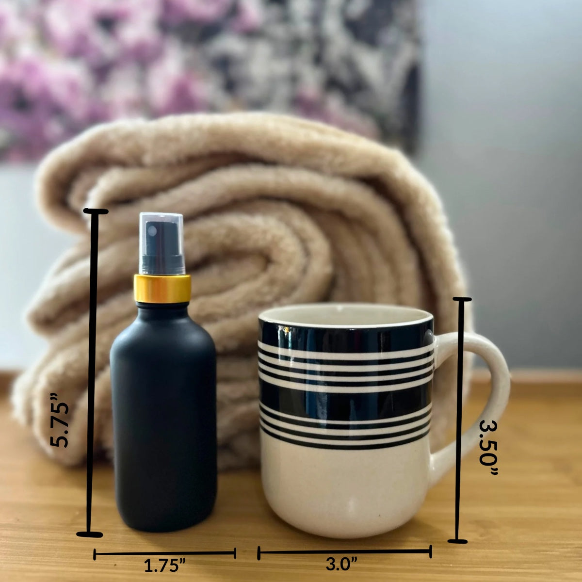 Reference photo comparing (height and width) our matte black spray bottle with gold neck to a black and wipe stripped coffee mug. 
